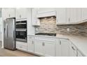 Modern kitchen featuring stainless steel appliances, white cabinets, a stylish backsplash, and a gas cooktop at 9530 Coastline Way, Parrish, FL 34219