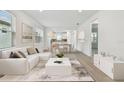 Bright, modern living room features an open floor plan, sleek white furniture, and stylish decor with hardwood floors at 9530 Coastline Way, Parrish, FL 34219