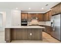 Modern kitchen with stainless steel appliances, a spacious island, and stylish wood cabinets at 10317 Cross River Trl, Parrish, FL 34219