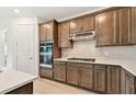 Well-equipped kitchen with stainless steel oven, range hood and appliances, quartz countertop and tiled backsplash at 10317 Cross River Trl, Parrish, FL 34219