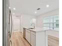 Kitchen island with sink, white cabinets, quartz countertop, and stainless steel dishwasher at 10414 Cross River Trl, Parrish, FL 34219