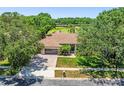 Aerial view of a home with a tile roof, three-car garage, and golf course views at 1084 Berkshire Ln, Tarpon Springs, FL 34688