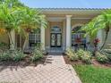 Inviting front entryway featuring double doors, decorative columns, and lush landscaping at 1084 Berkshire Ln, Tarpon Springs, FL 34688