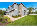 Desirable townhome featuring a two-car garage, lush lawn, and stone detailing at 30752 Veridian Way, Wesley Chapel, FL 33545