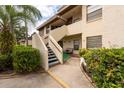 A walkway leads to a unit with covered entry, enhanced with greenery and a seating area at 3540 Countrybrook Ln # 23, Palm Harbor, FL 34684