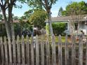 Exterior home view framed by a rustic wooden picket fence and mature trees at 3545 7Th N Ave, St Petersburg, FL 33713
