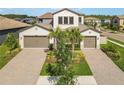 Beautiful two-story home featuring a three-car garage, brick driveway, and lush landscaping at 4365 Frontera Ln, Wesley Chapel, FL 33543