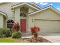Close-up of the front entrance with a red door, lovely landscaping, and a two-car garage at 5269 White Sand Ne Cir, St Petersburg, FL 33703