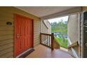 Condo entrance features a cheerful orange door and a glimpse of a serene lake view at 9481 Highland Oak Dr # 1206, Tampa, FL 33647