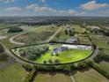Expansive aerial view of a picturesque farm with lush greenery, horse track, and modern equestrian facilities at 11602 Innfields Dr, Odessa, FL 33556