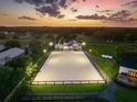 Well-lit equestrian arena at dusk with modern stables, horse paddocks, and adjacent farm house at 11602 Innfields Dr, Odessa, FL 33556
