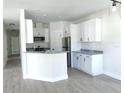 Modern kitchen with white cabinets, stainless steel appliances, granite countertops, and light wood-look floors at 1537 Palmetto St, Clearwater, FL 33755