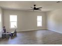 Spacious living room with wood-look flooring, two large windows, and a contemporary ceiling fan at 1537 Palmetto St, Clearwater, FL 33755