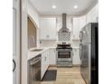 Well-lit kitchen featuring stainless steel appliances, white cabinetry, and wood flooring at 18228 Paradise Point Dr, Tampa, FL 33647