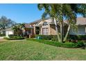 Well-maintained brick home with lush landscaping, including mature palm trees and manicured hedges at 2990 Eagle Estates W Cir, Clearwater, FL 33761