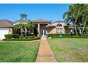 Beautiful brick home featuring manicured landscaping, palm trees, and a welcoming walkway at 2990 Eagle Estates W Cir, Clearwater, FL 33761