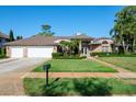 Charming brick home with a lush green lawn, manicured landscaping, and a three car garage at 2990 Eagle Estates W Cir, Clearwater, FL 33761