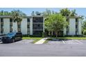 Condominium building exterior with a black car, parking, landscaping, walkway, and screened balcony at 3166 Lake Pine S Way # E3, Tarpon Springs, FL 34688