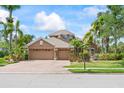 Inviting exterior with a three-car garage, surrounded by mature palms and well-maintained landscaping at 4111 70Th E Ave, Ellenton, FL 34222