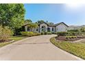 Picture-perfect home featuring a circular driveway, white brick, and lush green landscaping at 4677 Del Sol Blvd, Sarasota, FL 34243