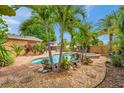 Lush backyard oasis featuring a sparkling pool, spa, tiki hut, and beautiful landscaping at 4815 Plantation Dr, Tampa, FL 33615