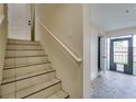 Staircase featuring ceramic tile steps, white handrail and leading to a lower level with stone tile floors at 5033 Blue Runner Ct, New Port Richey, FL 34652