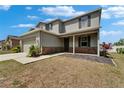 Charming gray home with stone accents, a covered porch, and lush landscaping at 11136 Hartford Fern Dr, Riverview, FL 33569