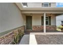 Inviting front porch with stone accents, a dark green door, and stylish lighting fixtures at 11136 Hartford Fern Dr, Riverview, FL 33569