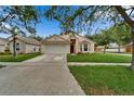 Inviting single-Gathering home featuring a lush front lawn, driveway, and a charming exterior design at 11626 Pure Pebble Dr, Riverview, FL 33569