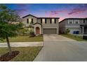 Inviting two-story home features a tidy front yard, cozy entrance, and convenient two-car garage at dusk at 16685 Parker River St, Wimauma, FL 33598