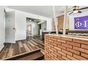 Open-concept living area with hardwood floors, a brick wall, and access to other rooms at 1902 W Nassau St, Tampa, FL 33607
