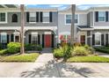 Charming townhome featuring a red door, lush landscaping, and beautiful palm trees at 273 Countryside Key Blvd, Oldsmar, FL 34677