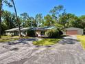 Charming single-story home with wood accents and a detached garage, complemented by a spacious driveway at 4310 Lithia Pinecrest Rd, Valrico, FL 33596