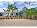 A charming light blue home features a brick walkway and meticulous landscaping with tropical plants at 504 69Th St, Holmes Beach, FL 34217