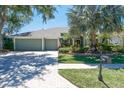 Inviting home featuring a three-car garage, brick-paved driveway, and beautifully maintained landscaping at 5269 Karlsburg Pl, Palm Harbor, FL 34685