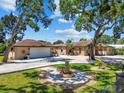 Charming home with a circular flower bed in the front yard and mature trees providing shade at 6732 Udell Ln, Hudson, FL 34667