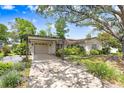 Charming single-story home featuring a large tree, two-car garage, and well-maintained landscaping at 7703 W Hiawatha St, Tampa, FL 33615