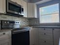 Updated kitchen features stainless steel appliances, modern backsplash, and white cabinetry, creating a bright and stylish space at 2333 Feather Sound Dr # B511, Clearwater, FL 33762