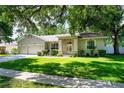 Traditional home with a beautiful lawn, mature trees, and a three-car garage at 2803 Bent Leaf Dr, Valrico, FL 33594