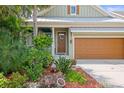 Close up view of the house, showing front door, front-facing garage and lush tropical landscaping at 7615 S Fitzgerald St, Tampa, FL 33616