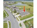 An aerial view of a single Gathering home showcasing the roof, landscaping, and neighborhood with a lake view at 8598 Parsons Hill Blvd, Wesley Chapel, FL 33545