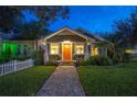 Charming bungalow with a brick path, vibrant orange front door and manicured landscaping at twilight at 938 16Th N Ave, St Petersburg, FL 33704