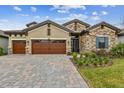 Charming home boasting stone accents, a three-car garage, brick driveway, and well-maintained landscaping at 11146 Rustic Timber Loop, San Antonio, FL 33576