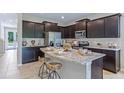 Modern kitchen with stainless steel appliances, granite countertops, dark wood cabinets, and an island with seating at 11393 Velvet Apricot Dr, Land O Lakes, FL 34638