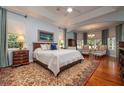 Tranquil bedroom with a tray ceiling, elegant lighting and comfortable sitting area at 2220 Muirfield Way, Oldsmar, FL 34677