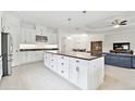 Spacious kitchen with white cabinets, black countertops, a large center island, and an open view of the living area at 29356 Ginnetto Dr, Wesley Chapel, FL 33543