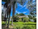 Charming single-story home with a yellow exterior, lush lawn, and mature trees in a desirable neighborhood at 3647 Lake St George Dr, Palm Harbor, FL 34684