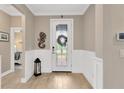 Inviting foyer with decorative front door, wood-look flooring, and elegant wainscoting at 5128 Dockyard Pl, Land O Lakes, FL 34638