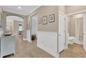 Hallway with wainscoting, wood-look flooring, and arched entryways to living spaces at 5128 Dockyard Pl, Land O Lakes, FL 34638