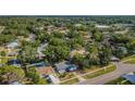 An aerial view of a neighborhood with mature trees and a blue single-story home with in ground pool at 9101 86Th Ave, Seminole, FL 33777